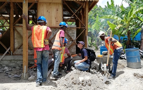 Un especialista del Cuerpo Suizo de Ayuda Humanitaria delante de una obra con especialistas haitianos. 