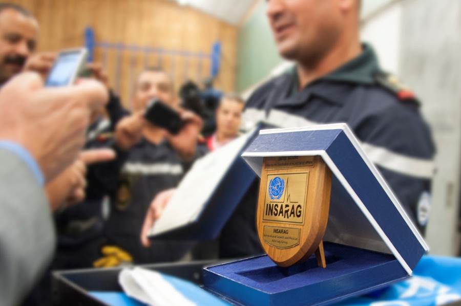 a Moroccan rescue worker holds up the INSARAG plaque and certificate. 