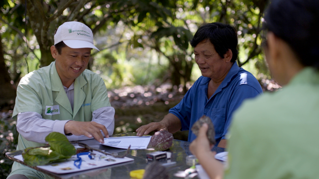 Ein vietnamesischer Pflanzendoktor berät zwei Bauern. 