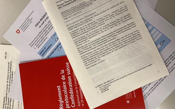Verschiedene Dokumente, wie etwa das «Wiener Übereinkommen über konsularische Beziehungen», liegen auf einem Tisch.