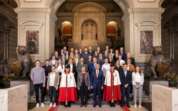 Le président Ignazio Cassis et la conseillère fédérale Viola Amherd avec une vingtaine d’athlètes à l’intérieur du palais du Parlement.