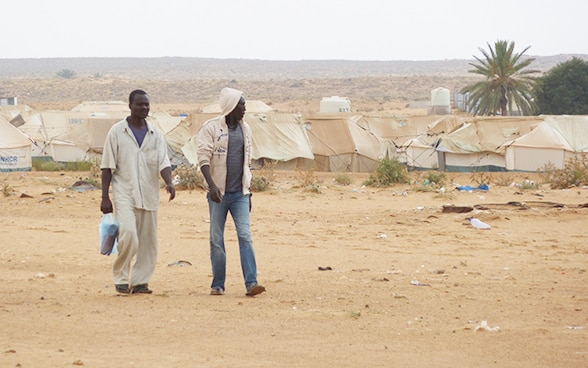 Deux migrants devant les tentes d'un camp de réfugié en Tunisie