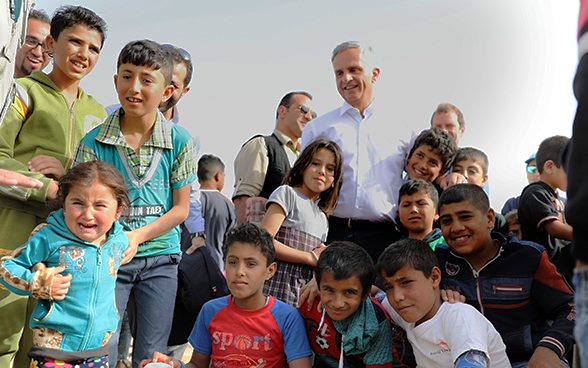 Une foule d’enfants réfugiés se tient au côté du chef du DFAE