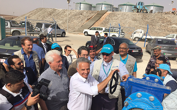 Le conseiller fédéral Didier Burkhalter tourne une roue qui permet d’activer le réseau d’eau potable pour le camp d’Azraq
