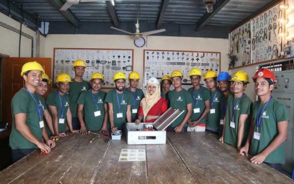 A group of men and a woman stand around a wooden table.