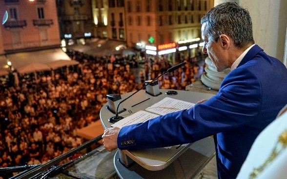Federal Councillor Ignazio Cassis speaks from a podium with the population in Lugano.  