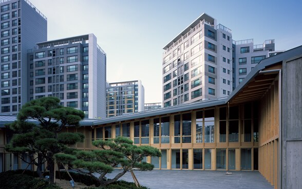 Aufnahme der Botschaft vom Innenhof aus. Im Hintergrund sind diverse Hochhäuser von Seoul zu sehen.