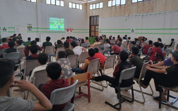 Des enfants syriens regardent un dessin animé dans une salle.