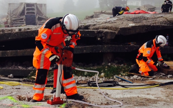 Vier Mitglieder der Rettungskette üben den Einsatz nach einem Erdbeben in einem gestellten Szenario auf einem Gelände in Epeisses.