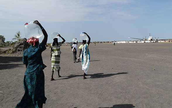 Südsudanesische Frauen tragen Wasserkanister auf dem Kopf