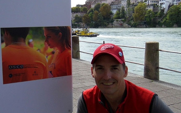 Le conservateur Ashley Woods devant le premier panneau de l’exposition de photos « Making Peace», sur les bords du Rhin à Bâle
