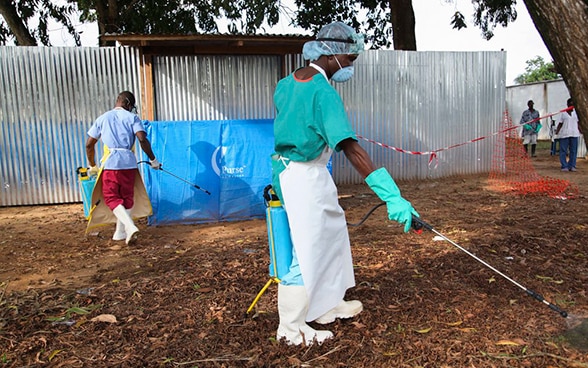 A nurse in Liberia sprays disinfectant as a preventive measure against Ebola.