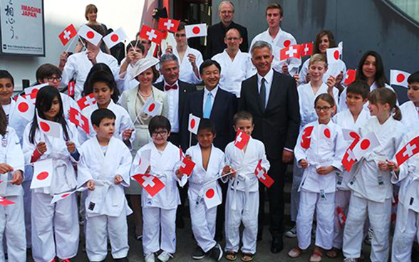 Bundespräsident Didier Burkhalter und der japanische Kronprinz Naruhito mit Kindern, die kleine Flaggen der Schweiz und Japans in den Händen halten.