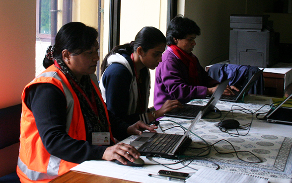 Local staff of the Swiss embassy in Nepal working at a table. 