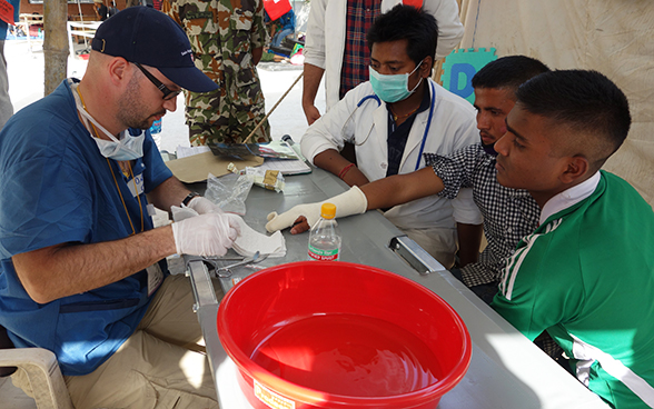 Ein Mitglied des medizinischen Teams aus der Schweiz verbindet die verletzte Hand eines Erdbebenopfers in Nepal. 