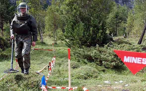 Ein Angehöriger der Schweizer Armee kontrolliert mit einem Detektor ein improvisiertes Minenfeld im Gasterntal bei Kandersteg (2001).