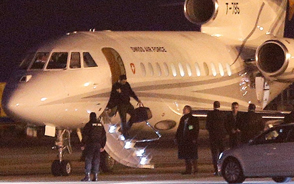 Ein Mann verlässt ein Flugzeug der Schweizer Air Force in Genf. Davor stehen Sicherheitskräfte und andere Personen.