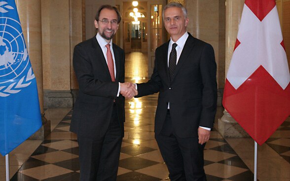 Federal Councillor Didier Burkhalter with the UN High Commissioner for Human Rights Zeid Ra’ad Al-Hussein in the Federal Palace in Bern, with the Swiss and UN flags on either side.