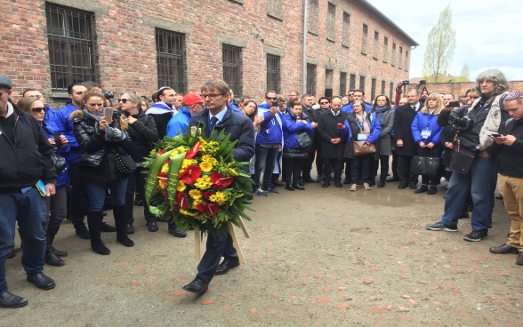 Benno Bättig, Chair of the International Holocaust Remembrance Alliance (IHRA), lays a wreath at the Death Wall in Auschwitz during the March of the Living