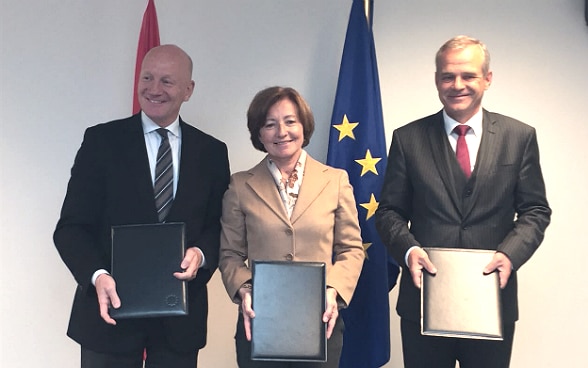 Manuel Bessler et Benno Bühlmann signent l’accord avec la représentante de l’UE, Monique Pariat