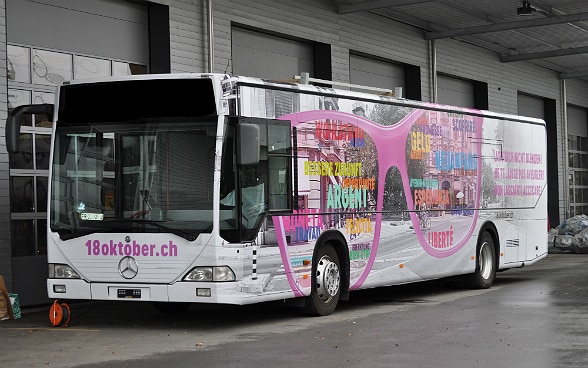 Un bus multicolore est en arrêt devant un garage.