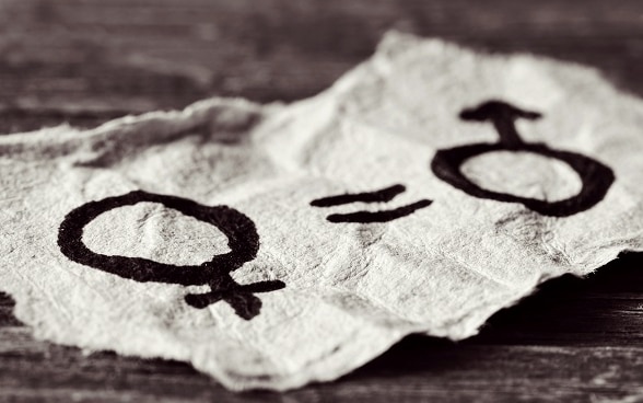 Le symbole d’une femme, le signe «est égal» et le symbole d’un homme sont dessinés sur une feuille de papier.