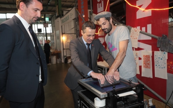 During his visit to the Muba18, Federal Councillor Ignazio Cassis practices screen printing.