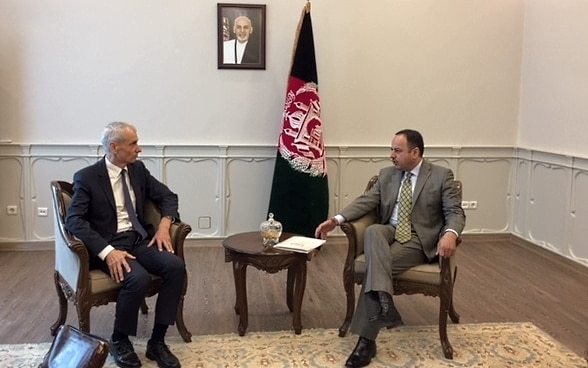 Botschafter Thomas Kolly und der afghanische Finanzminister H.E. Eklil Hakimi während der Unterzeichnung des Rahmenabkommens an einem Tisch. Im Hintergrund sind die Flaggen der beiden Staaten zu sehen.