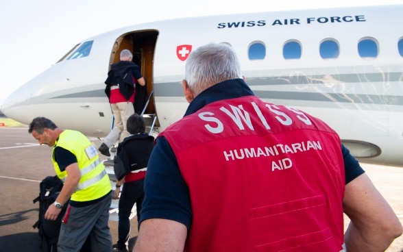 Experten des Schweizerischen Korps für Humanitäre Hilfe (SKH) steigen in in Belp in ein Flugzeug der Schweizerischen Eidgenossenschaft.