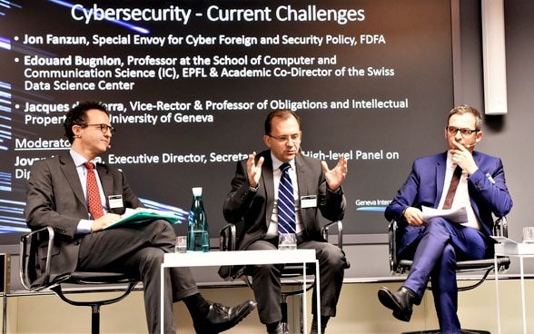 Teilnehmer der Diskussion zur Cybersicherheit tauschen sitzend auf dem Podium aus.