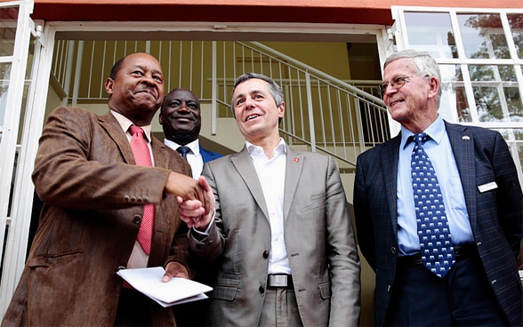 Bundesrat Ignazio Cassis schüttelt die Hand des simbabwischen Gesundheitsministers Obadiah Moyo, während Professor Ruedi Luthy, Gründer einer von der Schweiz finanzierten Klinik, bei seinem Besuch zusieht.