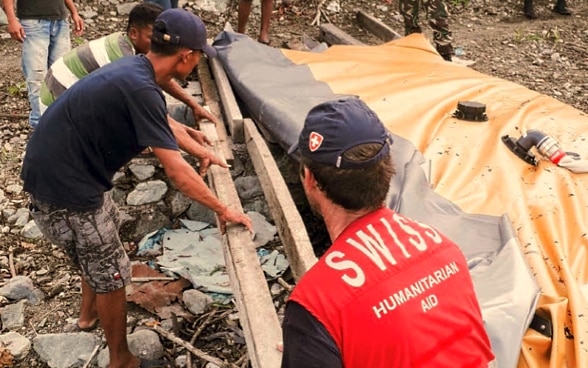 Ein Mitglied des Schweizerischen Korps für Humanitäre Hilfe hilft der lokalen Bevölkerung beim Wiederaufbau von Wasserinfrastruktur nach einer Katastrophe.