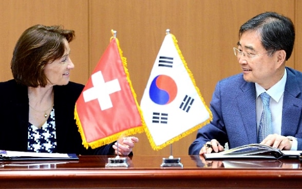 Pascale Baeriswyl and Cho Hyun sit at a wooden table and talk.