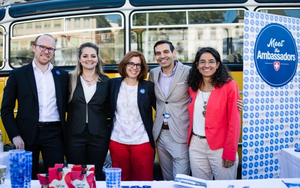 Un groupe de cinq ambassadrices et ambassadeurs posent pour devant le bus jaune pour la photo