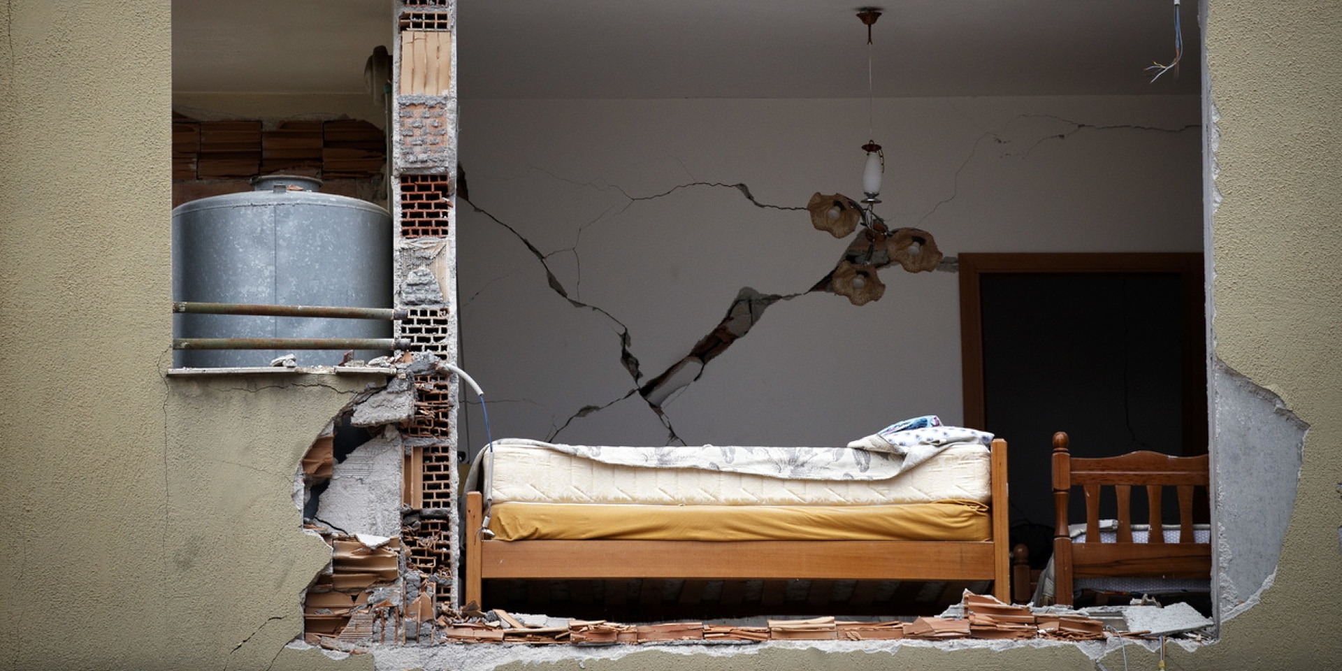 Immeuble d’habitation dont la façade a été éventrée. Le trou provoqué par le séisme laisse entrevoir l’intérieur d’une chambre à coucher.