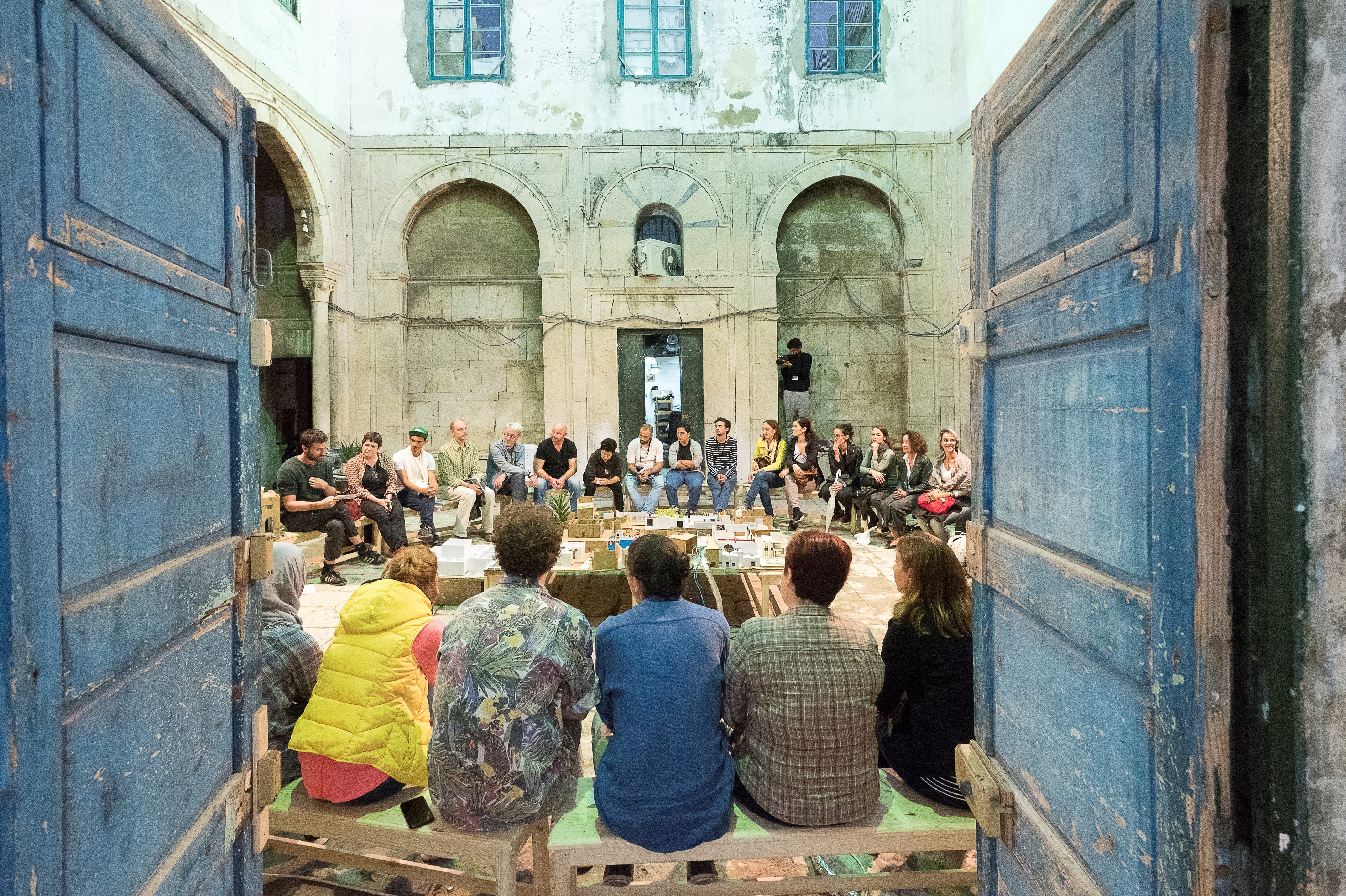 A group of young people sit in a circle in the inner courtyard of a building during the Dream City festival in Tunis.