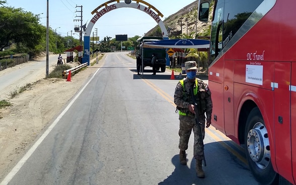 At a checkpoint, a soldier checks if the bus has permission to pass through.
