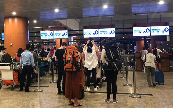 Dans le hangar de l'aéroport de Yangon, les passagers font la queue devant les comptoirs d'enregistrement.