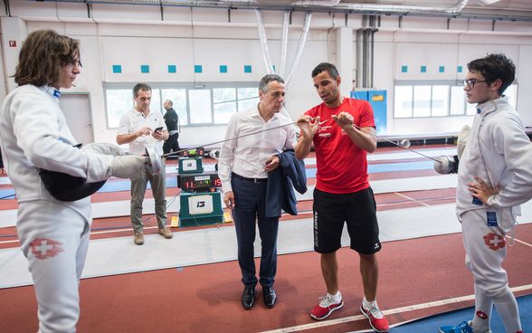 Federal Councillor Ignazio Cassis talks to a fencer in the school gym. 