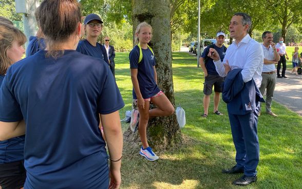 Il consigliere federale Ignazio Cassis parla con gli atleti di atletica leggera all'aperto. 