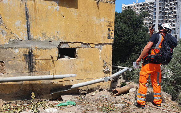 An expert from the Swiss Humanitarian Aid Unit takes a photo of a destroyed house.