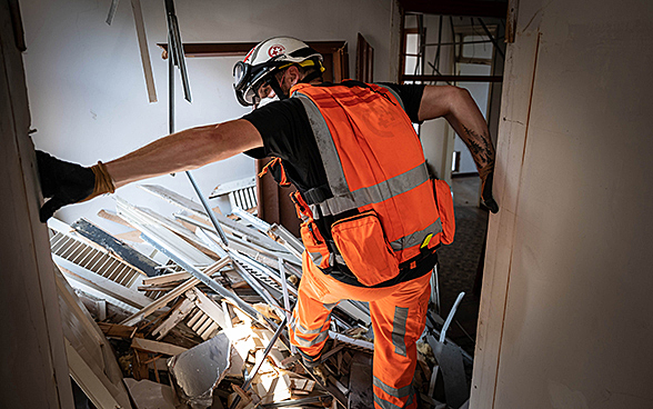 Ein Experte der Humanitären Hilfe des Bundes steigt über Trümmer in einem Haus. 