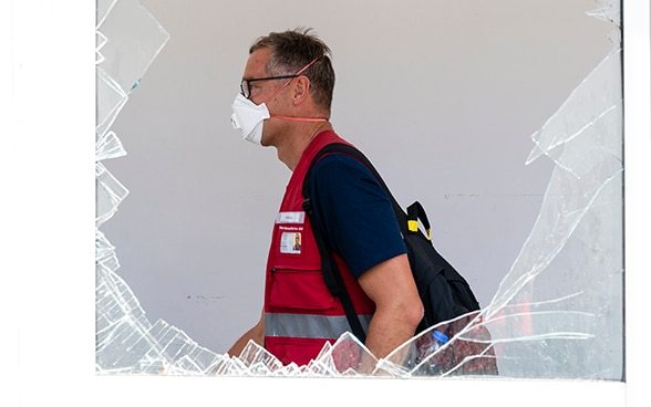 Vue sur un expert de l'Aide humanitaire suisse à travers la fenêtre brisée d'un hôpital.