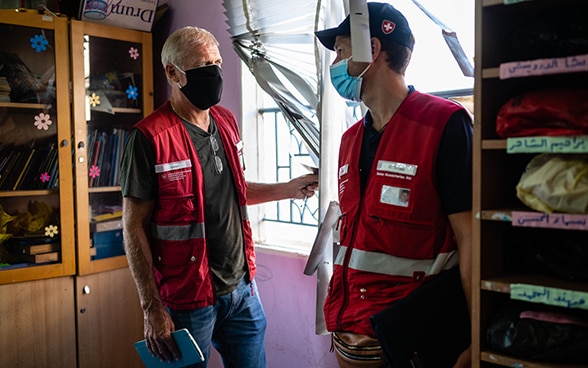 Zwei Experten der Humanitären Hilfe des Bundes unterhalten sich in einem zerstörten Klassenzimmer.