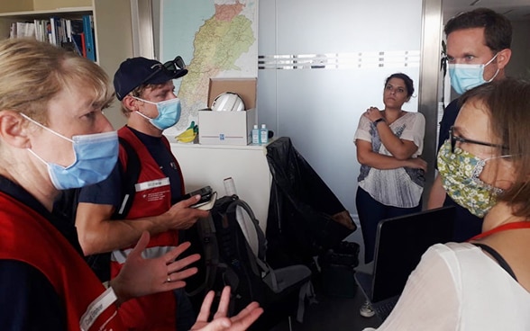 Experts from Swiss Humanitarian Aid inform each other about their tasks in a room.