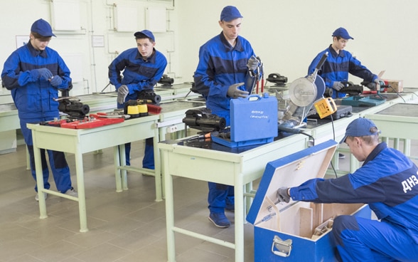 Fünf Auszubildende arbeiten in der Werkstatt einer Berufsschule in der Ukraine.