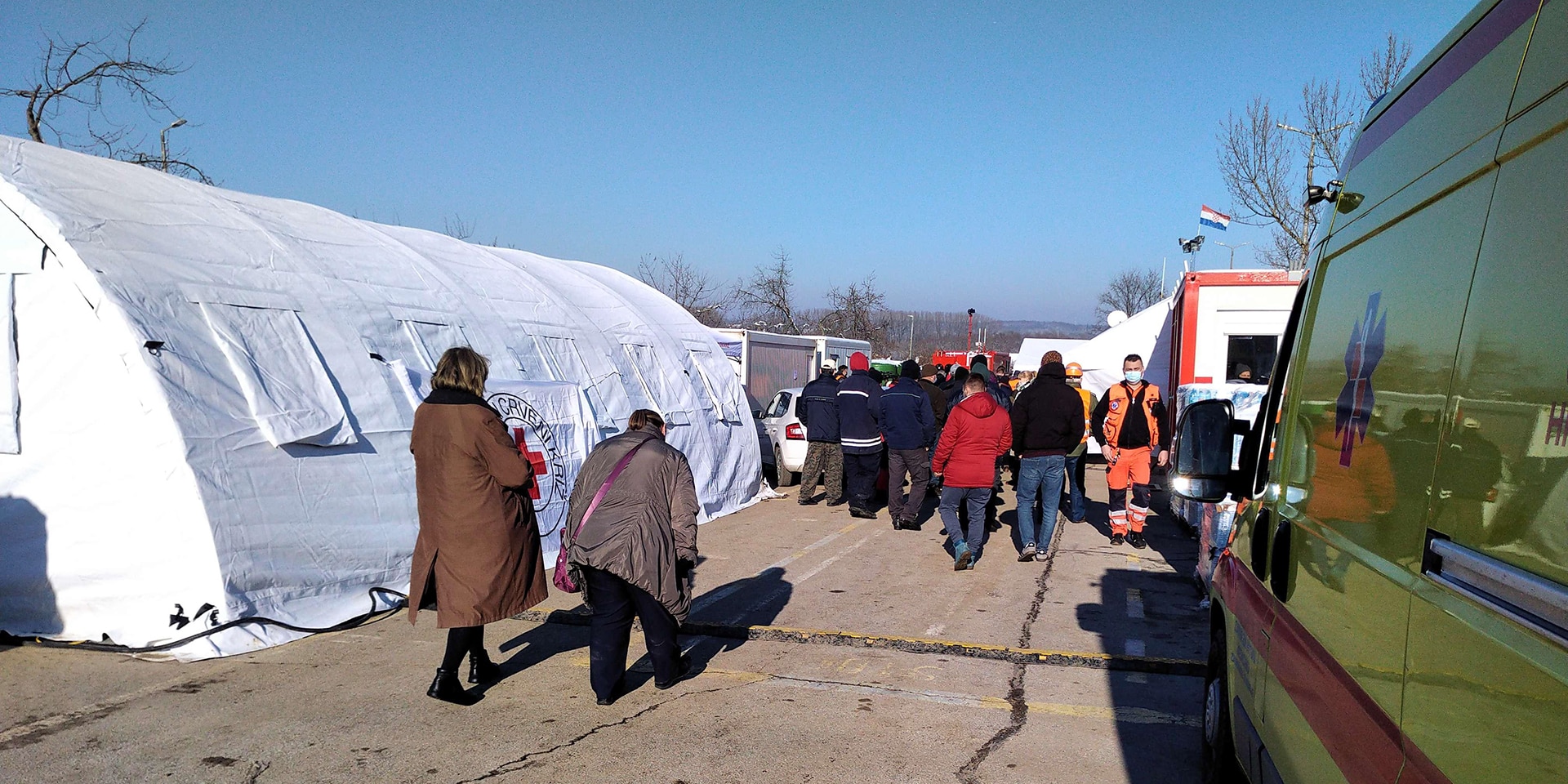 Ein weisses Zelt, ein Krankenwagen und weitere Fahrzeuge des Zivilschutzes und der humanitären Organisationen. Einsatzkräfte leisten Hilfe.
