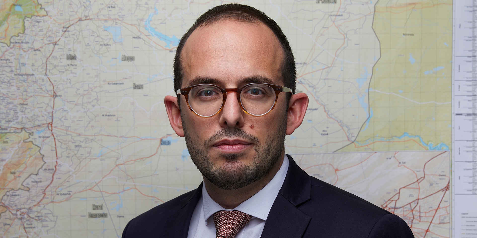 Close-up of Luca Urech in front of a map of Syria.