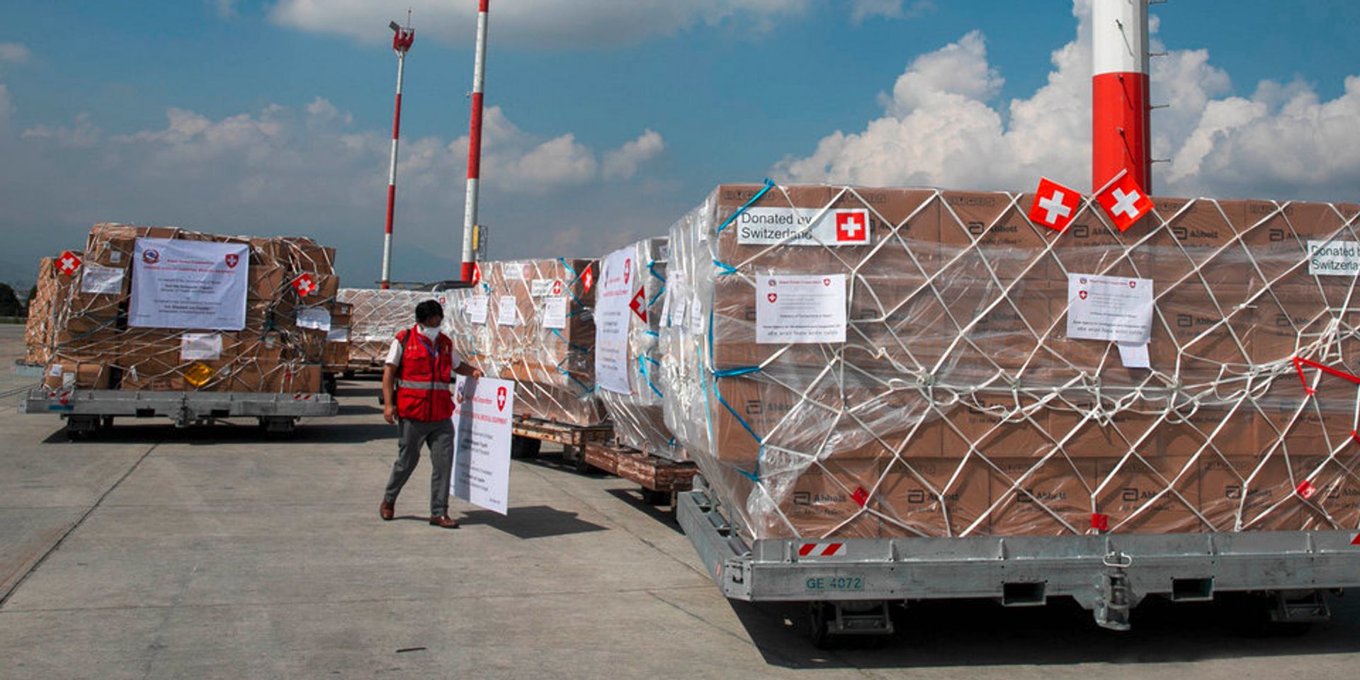 Veicoli sulla pista dell’aeroporto trasportano pacchi con aiuti umanitari verso il magazzino. 