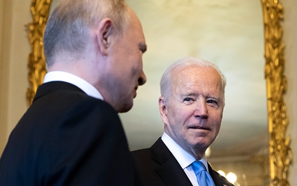 Präsident Joe Biden und Präsident Wladimir Putin stehen vor einem Spiegel und blicken sich an.